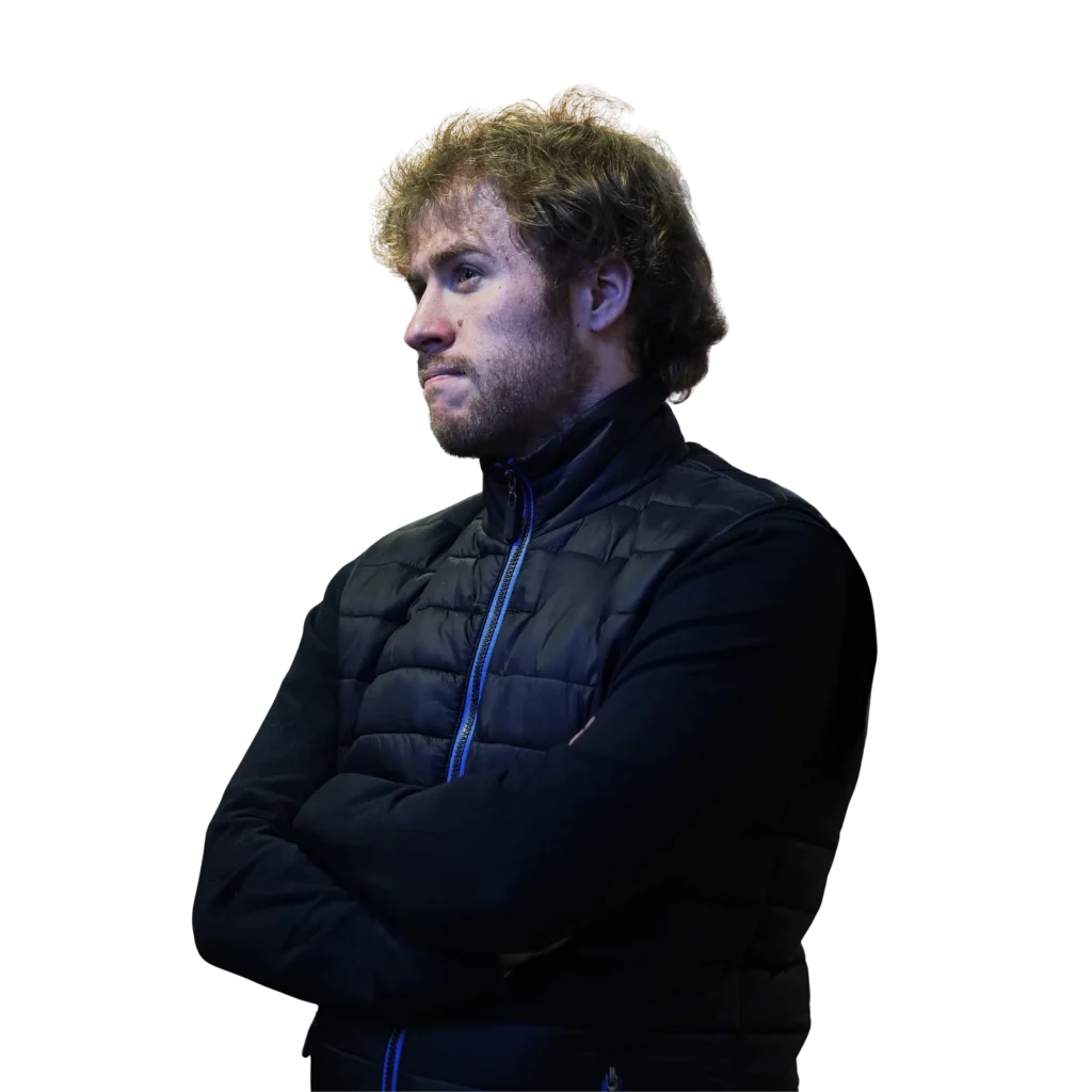 Mon parcours Une image de Franck Gregoire, freelance communication digitale, croisant les bras avec un regard pensif, portant une doudoune sans manches et un pull à manches longues.